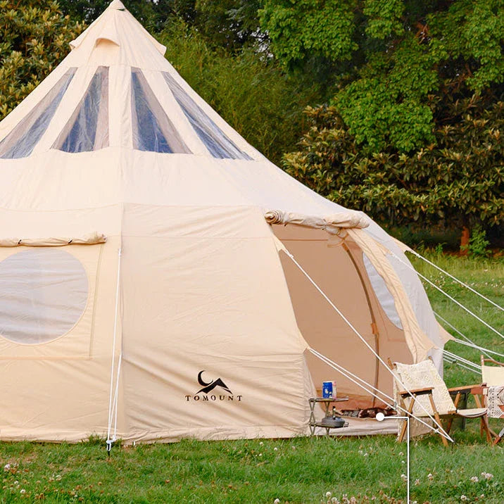 Large beige canvas camping tent with mesh windows set up outdoors on green grass