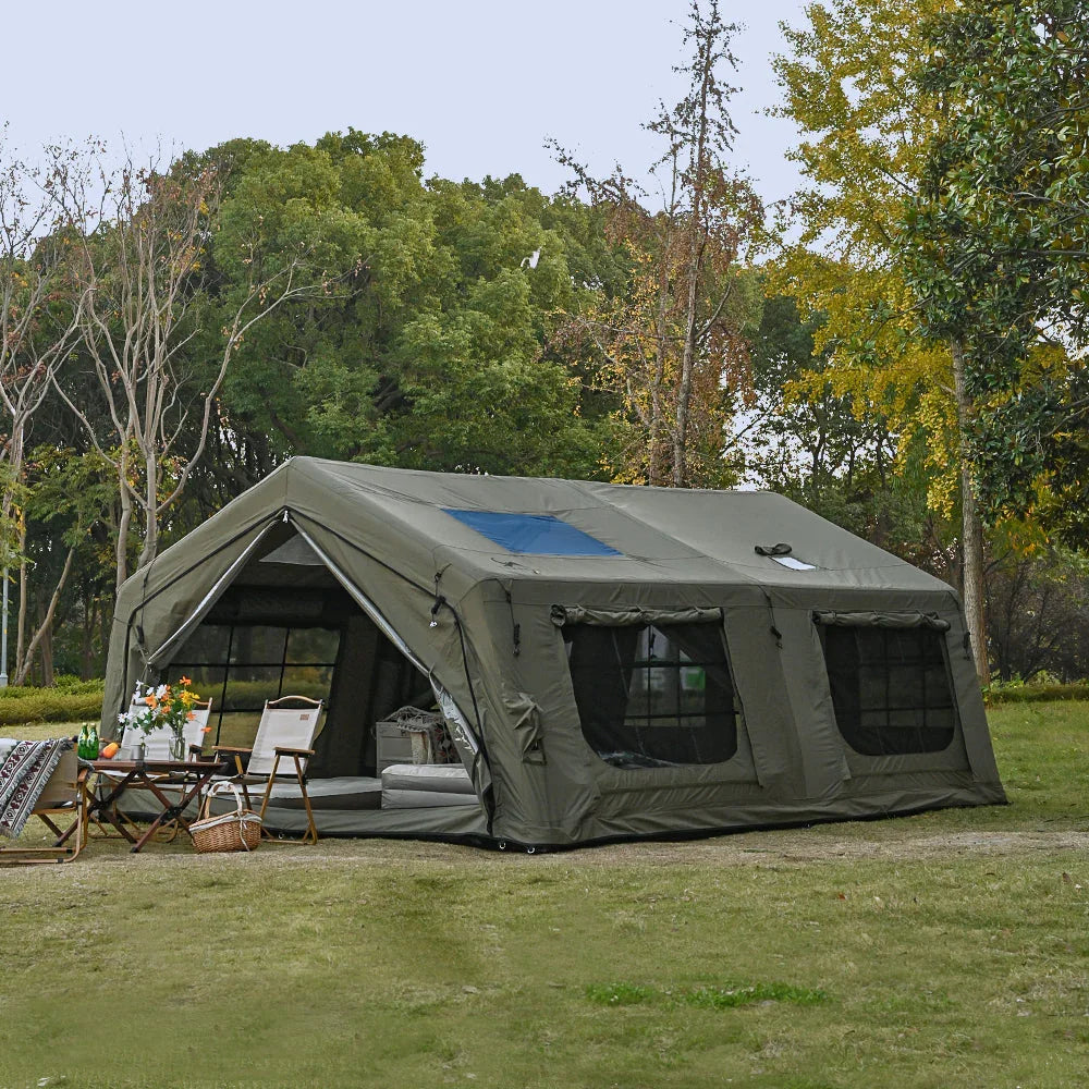 Large green canvas camping tent set up outdoors with folding chairs and picnic table