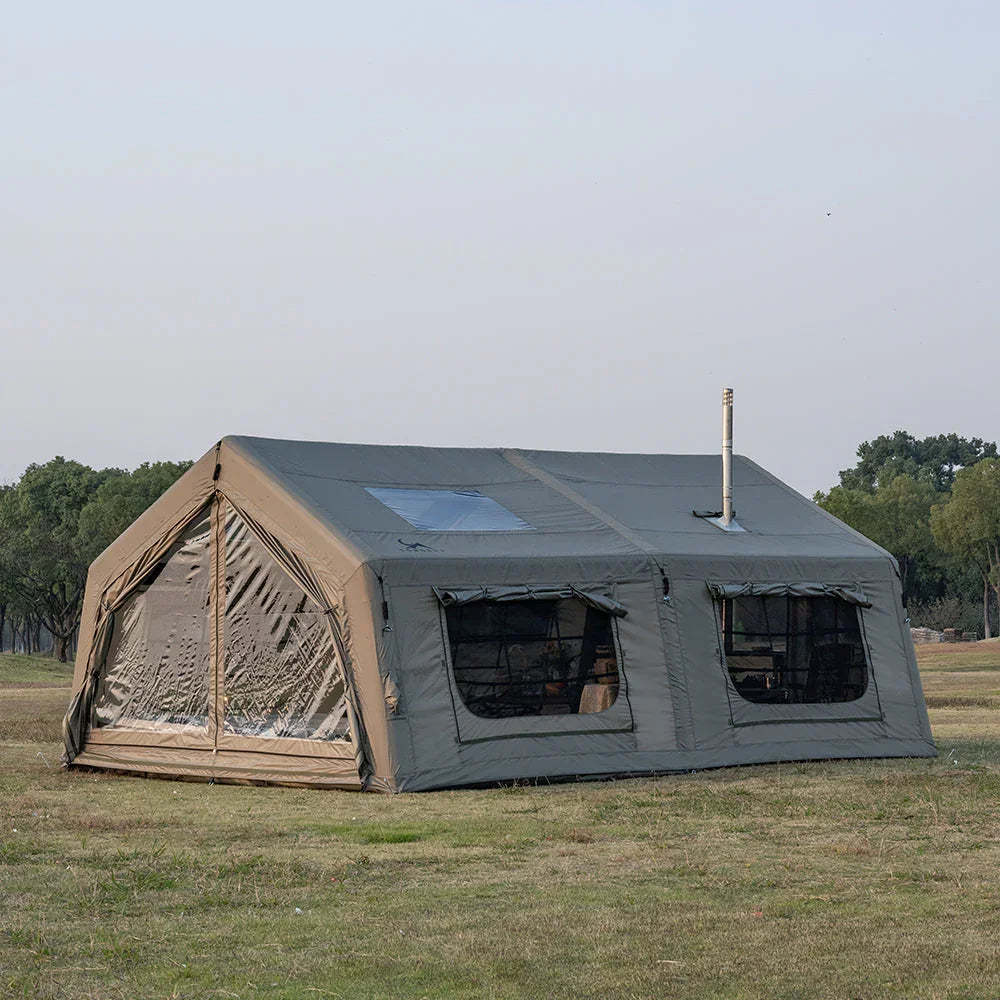 Large canvas camping tent with windows and stove jack set up on grassy field outdoors