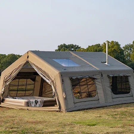 Large canvas wall tent with stove jack, mesh windows, and outdoor camping setup on grass