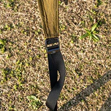 Tent strap and stake securing fabric to grass ground outdoors