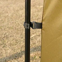 Close-up of a tent pole and fabric strap securing a tan outdoor tent on grass
