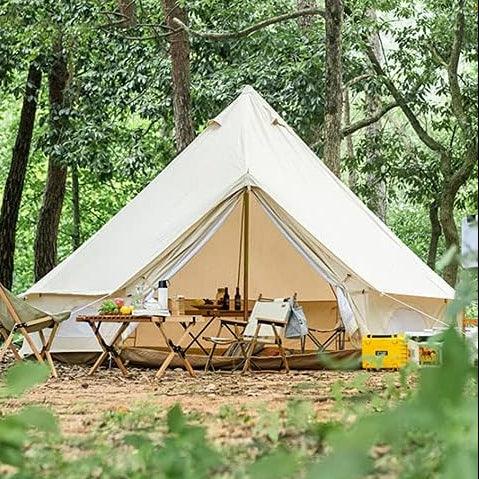 Large canvas bell tent set up in forest, surrounded by camping chairs and picnic table