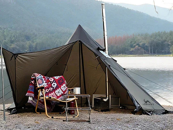Lakeside camping tent with outdoor chair, patterned blanket, and portable stove setup