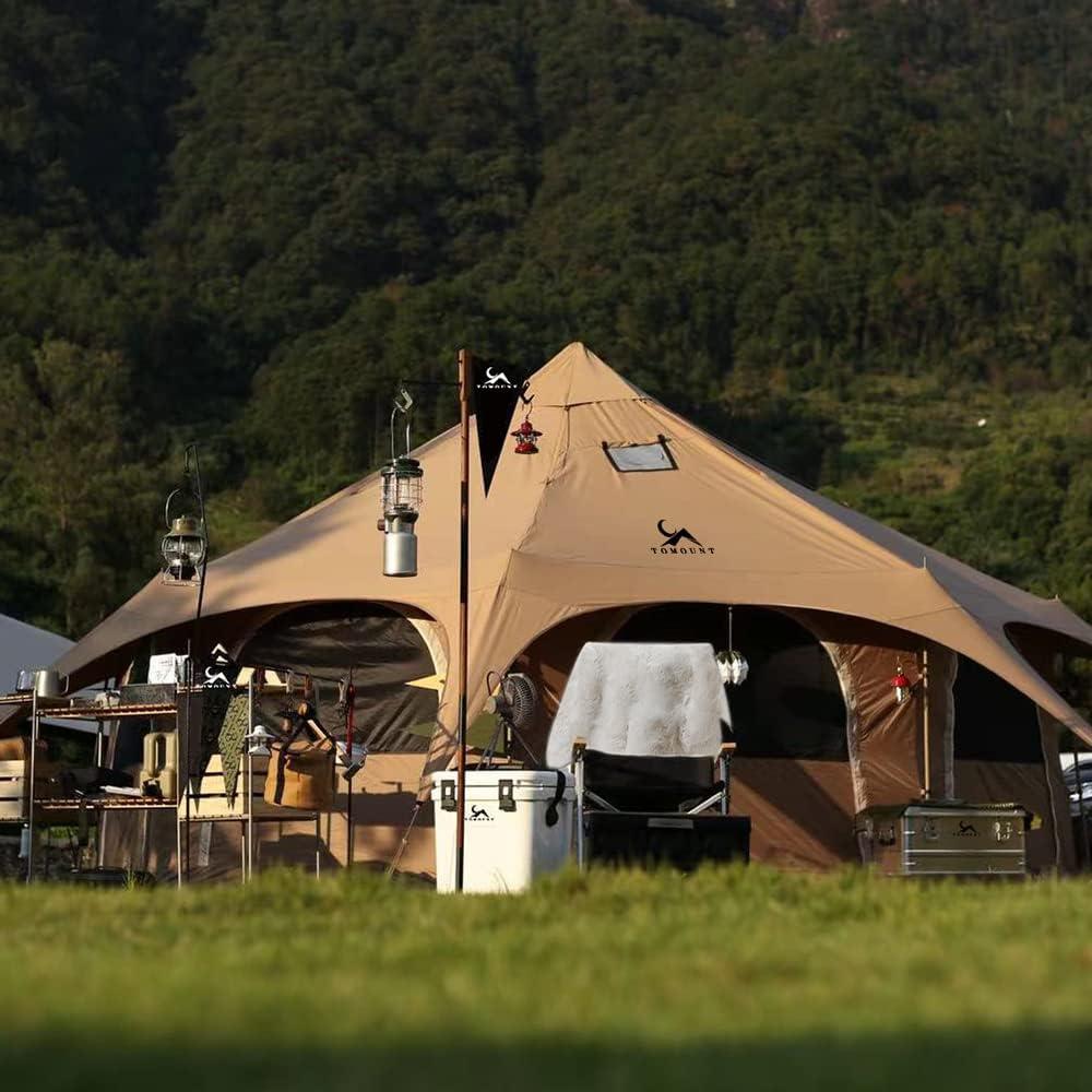 Large beige canvas tent set up for camping outdoors with gear and lanterns, surrounded by green forest