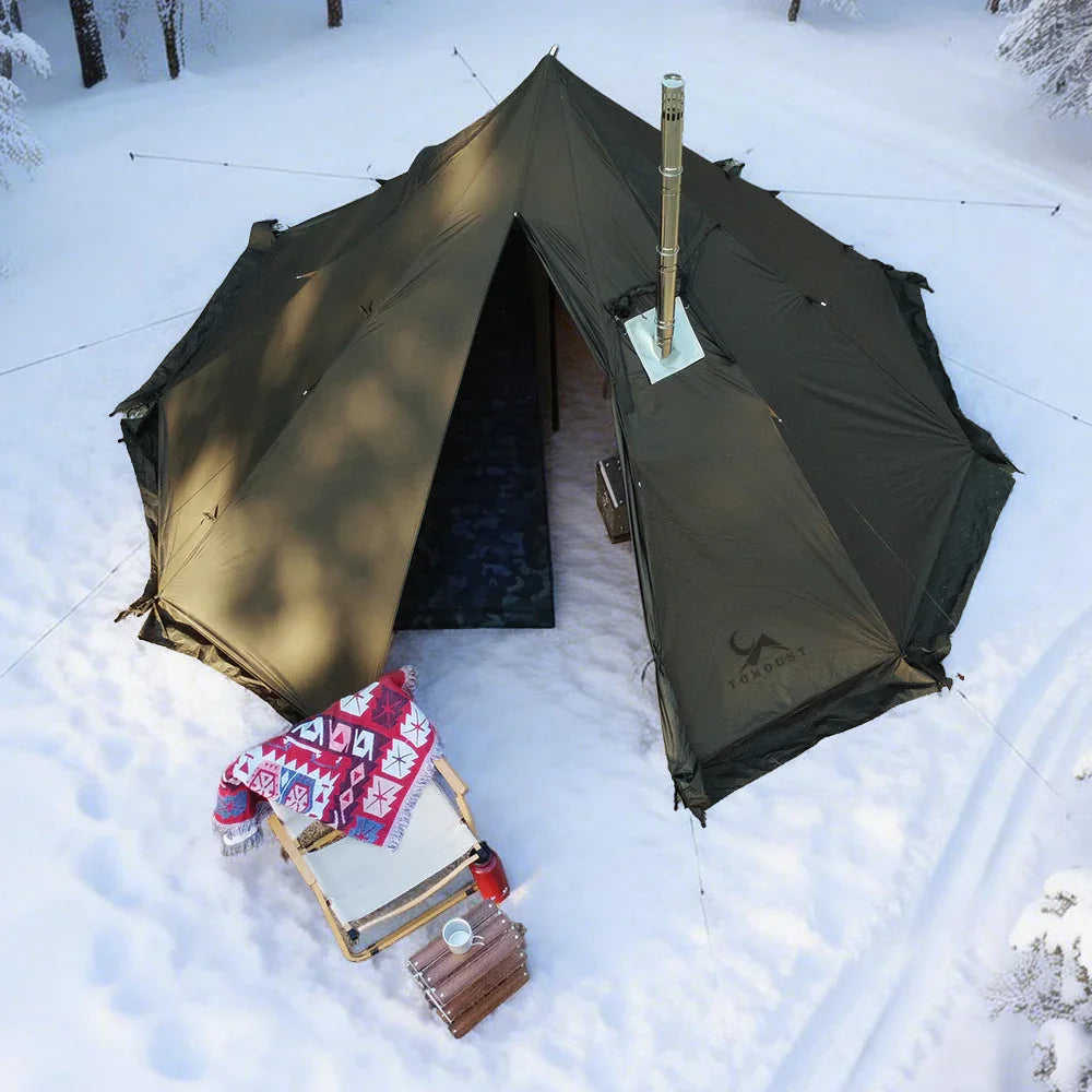 Large green winter camping tent with stove in snowy forest, folding chair and blanket